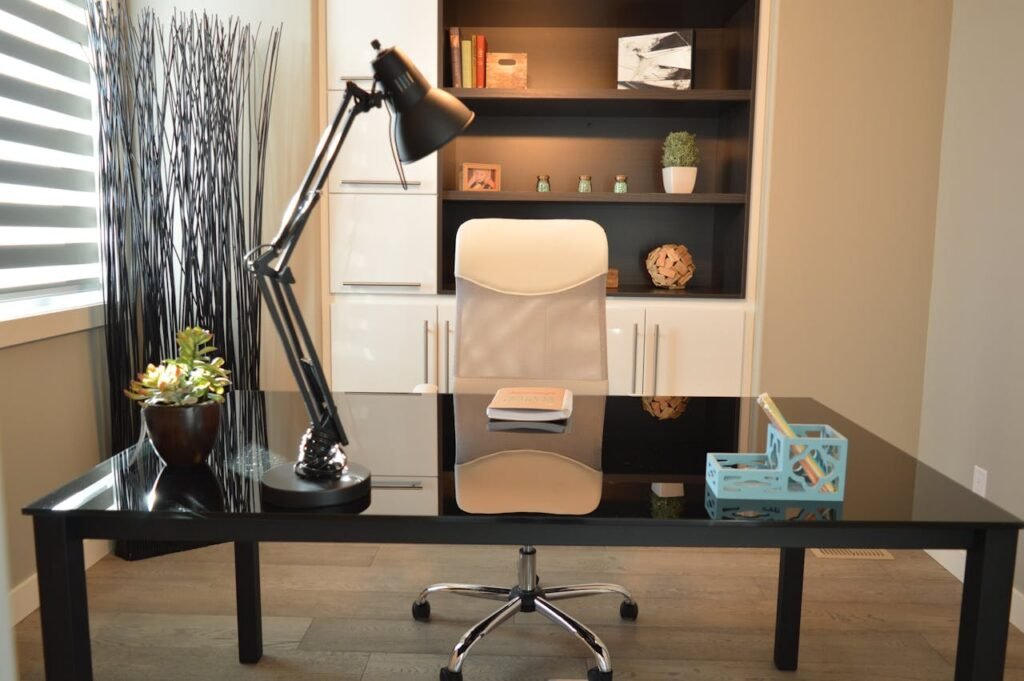 office home house desk 159839 1 Stylish modern office workspace featuring a black desk, lamp, and white chair with shelving.